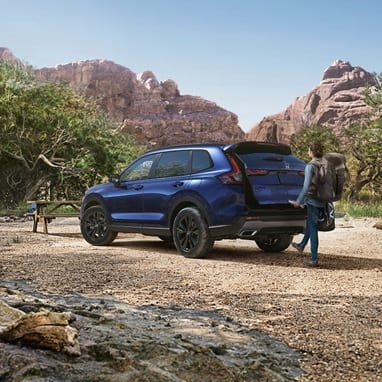2027 Honda CR-V Sport Touring Hybrid in Canyon River Blue Metallic parked in a mountain landscape (Compact Crossover SUV).